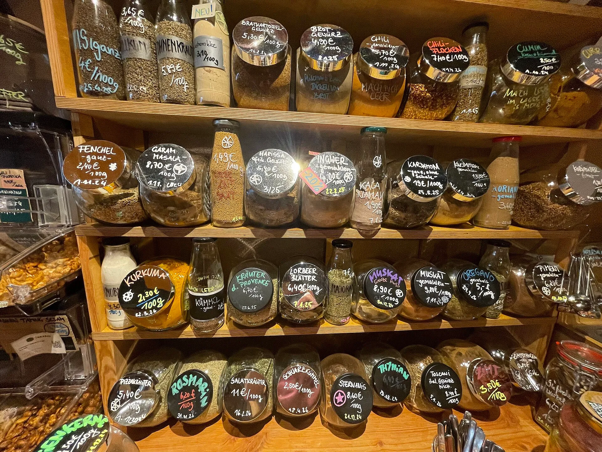 Étagère en bois garnie de bocaux de vrac, épices et herbes, aux étiquettes écrites à la craie