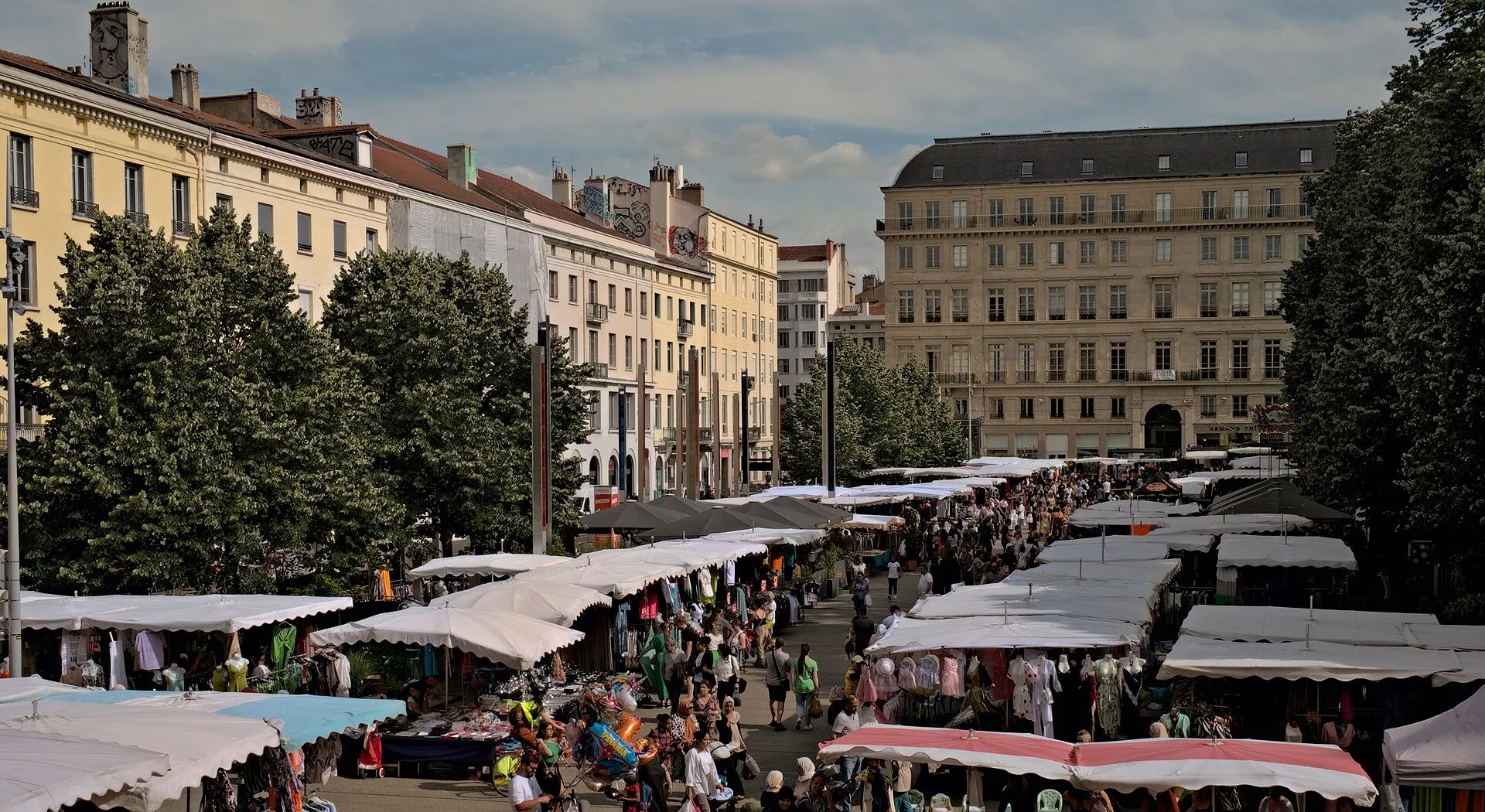 Grande braderie de seconde main sur une place de Saint-Étienne, étals sous des auvents blancs